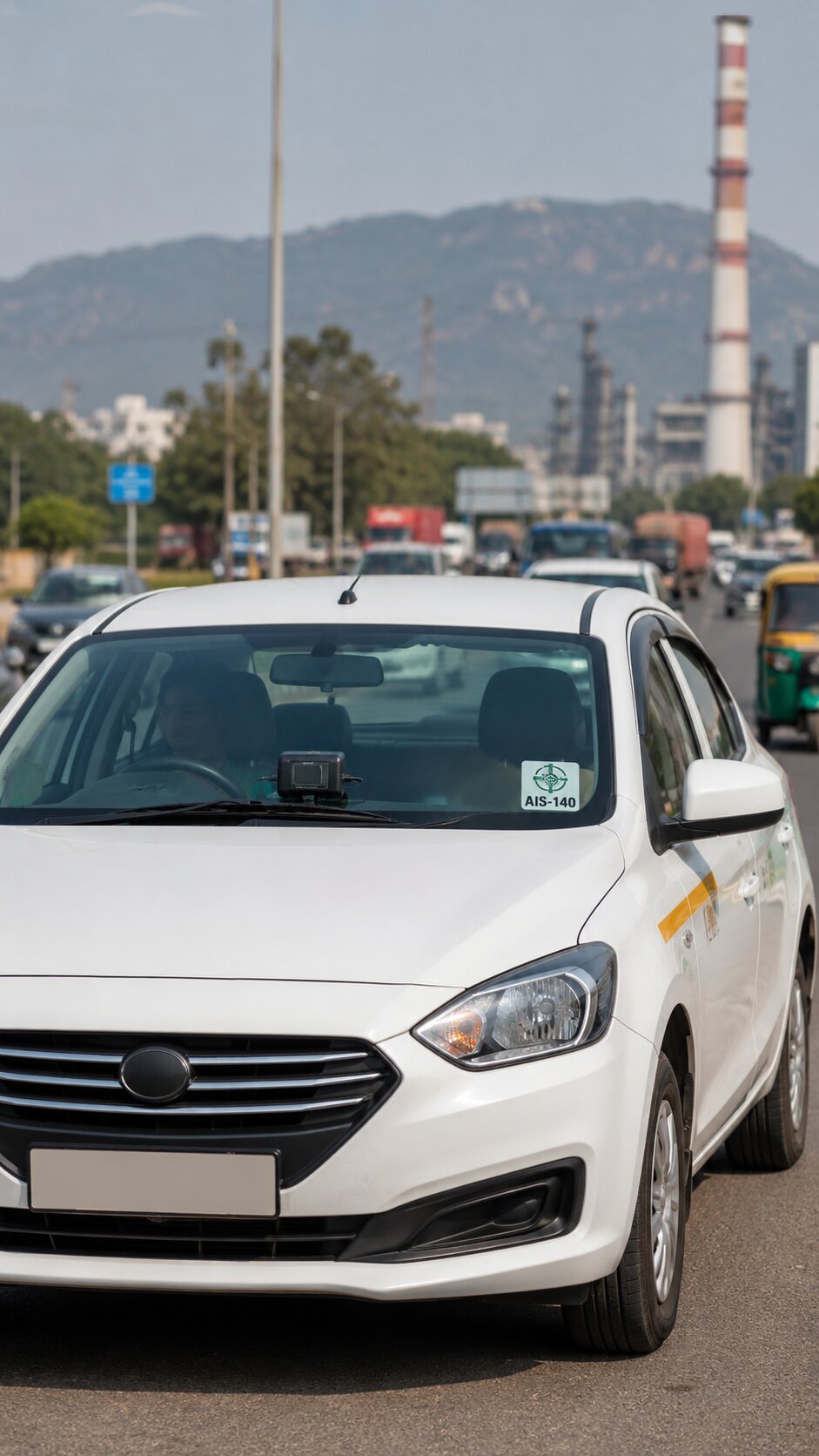 Photorealistic street-level photograph of a white sedan cab on a wide Faridabad road with the softly blurred outline of an industrial plant chimney stack or the Aravalli Hills ridge visible in the background. GPS device mounted on the dashboard visible through the windshield. AIS-140 sticker on the lower right corner of the windshield. Clean daylight, busy industrial NCR city atmosphere. No logos, no brand text, no license plates.