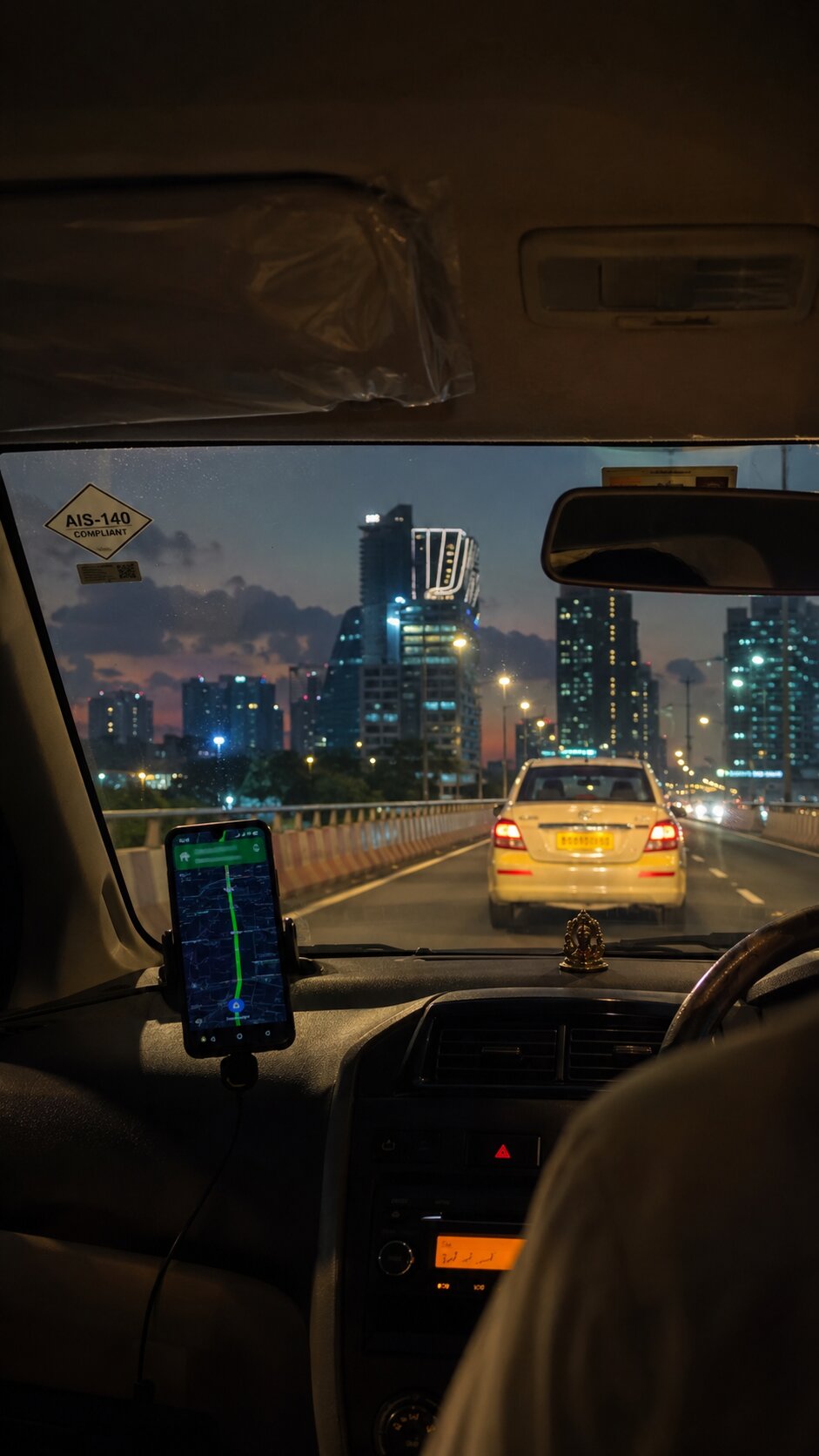 AIS-140 compliant taxi driving through Bengaluru at night with live GPS route visible on the dashboard phone